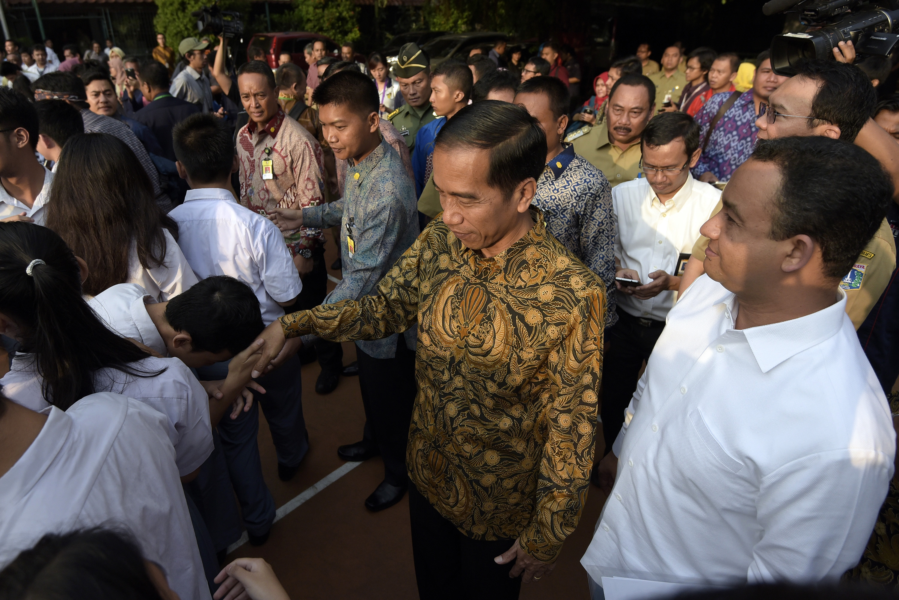 Presiden Joko Widodo (tengah) didampingi Menteri Kebudayaan dan Pendidikan Dasar dan Menengah Anies Baswedan (kanan) menyalami para peserta Ujian Nasional (UN) di SMA N 2 Jakarta, Jakarta, Selasa (14/4). (Foto: Gulalives/Ant)