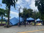 Beberapa tenda stan jualan berwarna biru milik pedagang di Alun-alun Pacitan terlihat roboh, miring, dan rusak di atas area berlantai paving pada hari Sabtu (24/1/2026), akibat terpaan angin kencang yang dipicu oleh Siklon Tropis Luana.
