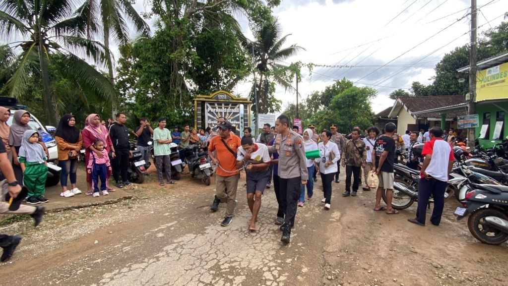 Kapolres Pacitan AKBP Ayub Diponegoro Azhar menuntun warga ODGJ korban pasung didampingi tim Ipda Purnomo saat proses evakuasi rehabilitasi di Desa Petungsinarang, Kecamatan Bandar, Pacitan.