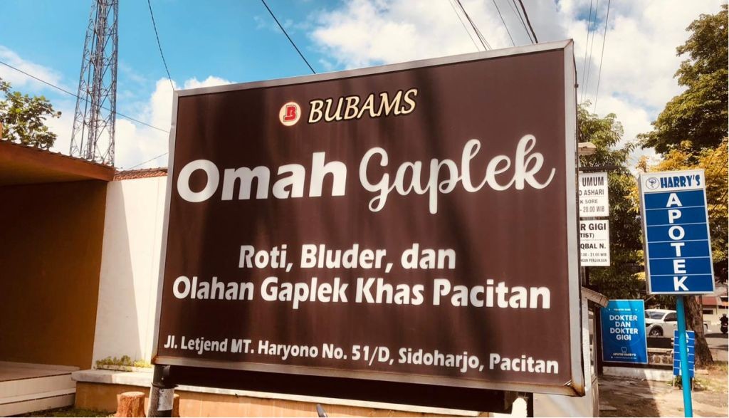 Tampilan brownies gaplek dengan topping almond yang diproduksi oleh Omah Gaplek Pacitan, disajikan di atas piring kayu dengan latar belakang bahan baku singkong.