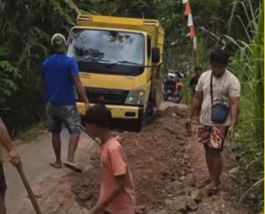 Anggota komunitas Bolo Roda dan armada truk sedang melakukan perbaikan jalan rusak secara swadaya di wilayah Kalikuning, Pacitan.