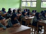 Sejumlah siswi SMPN 4 Nawangan berjilbab biru dan berseragam batik duduk tertib di bangku kayu di dalam kelas saat mengikuti program Sekolah Sak Ngajine.