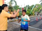 Panitia El John Fun Run sedang mengalungkan medali kepada pelari muda yang mencapai garis finis pada acara El John Fun Run di kawasan wisata Teleng Ria, Pacitan.