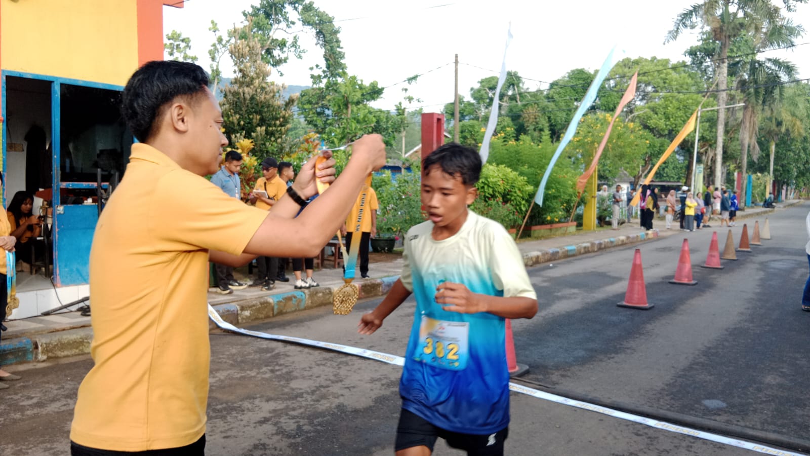Panitia El John Fun Run sedang mengalungkan medali kepada pelari muda yang mencapai garis finis pada acara El John Fun Run di kawasan wisata Teleng Ria, Pacitan.