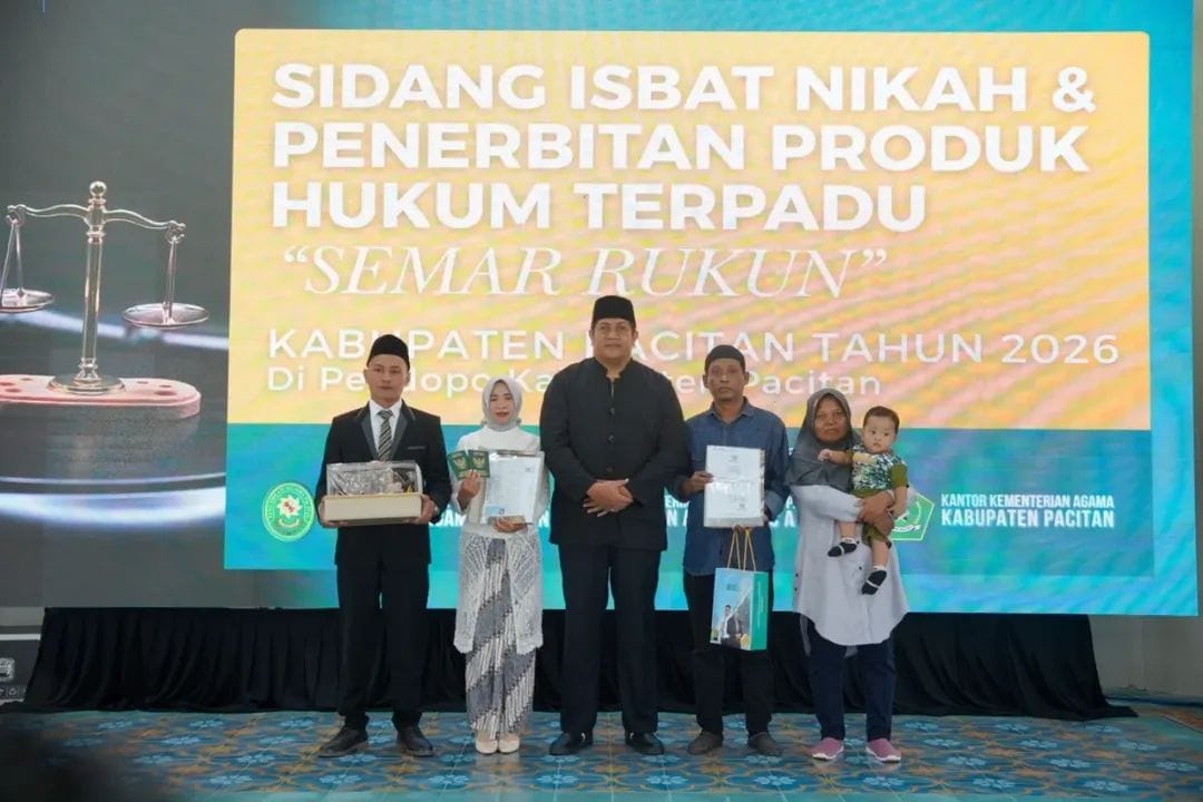 Wakil Bupati Pacitan, Gagarin Sumrambah (tengah, berpeci hitam), berfoto bersama perwakilan pasangan suami istri peserta program Sidang Isbat Nikah Terpadu "Semar Rukun" tahun 2026 di atas panggung Pendopo Kabupaten Pacitan. Peserta di sisi kiri dan kanan terlihat memegang dokumen kependudukan dan Buku Nikah yang baru diterima dengan latar belakang spanduk acara.