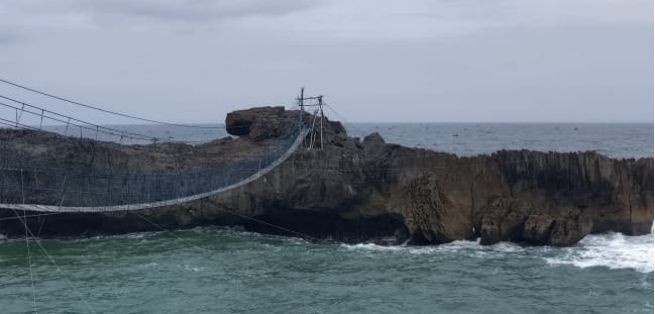 Batu karang raksasa ikonik di Pantai Watu Bale Pacitan yang dihantam ombak besar pantai selatan saat suasana senja yang dramatis.