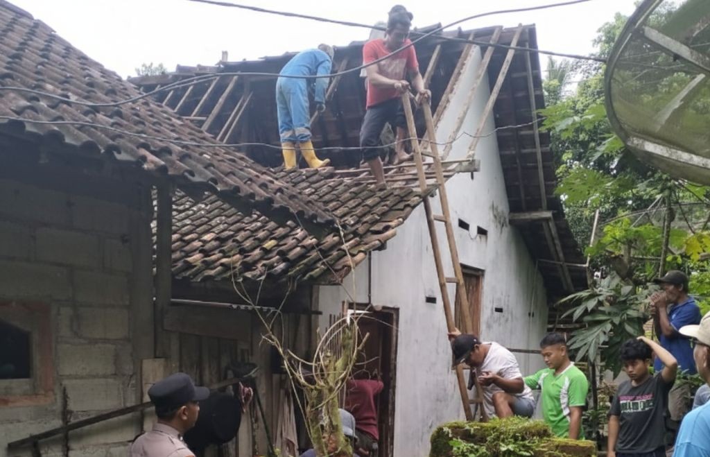 Warga dan petugas bekerja bakti memperbaiki atap rumah yang rusak akibat gempa di Desa Kedungbendo, Pacitan.