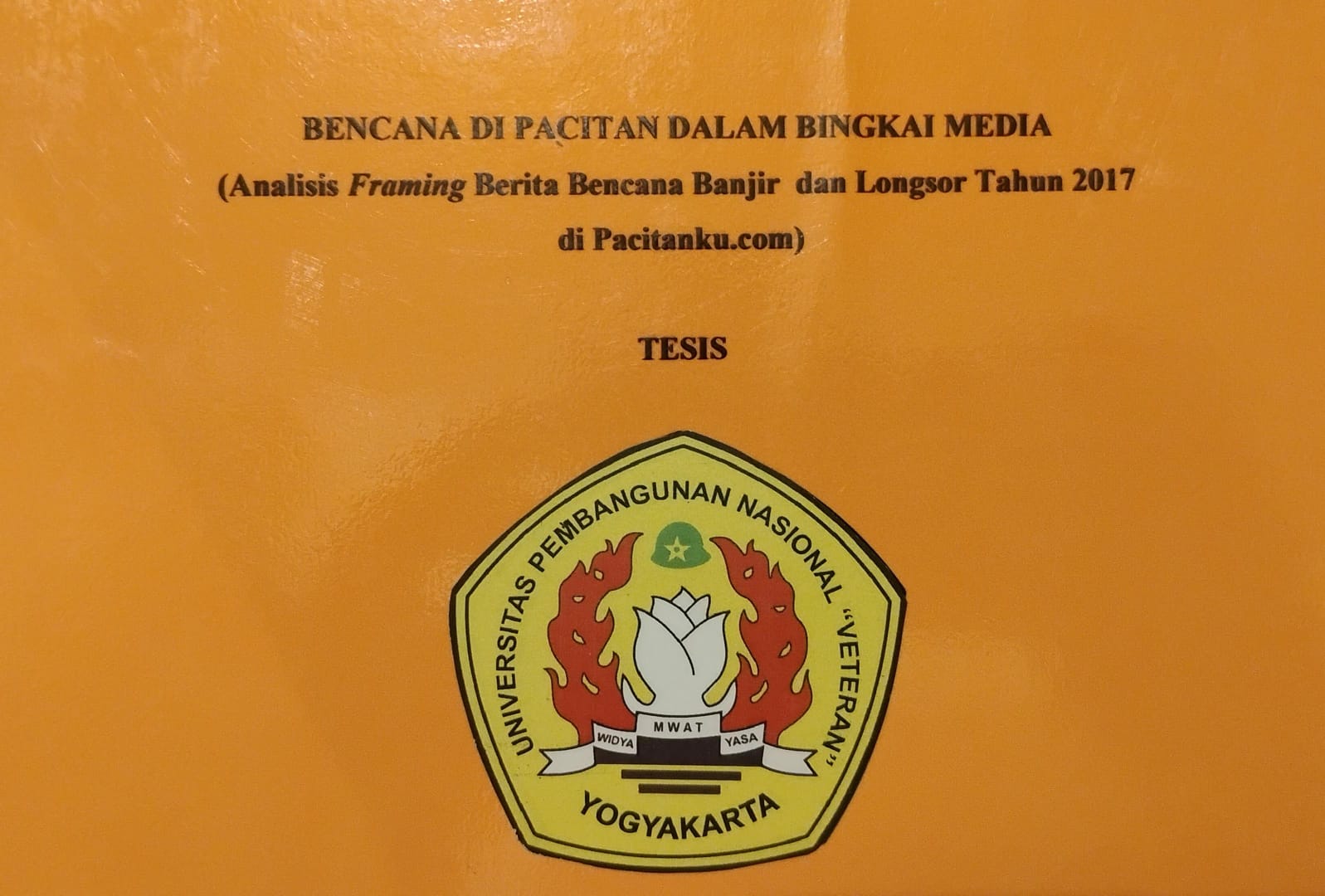 Foto sampul depan dokumen tesis berwarna oranye dengan judul tercetak: "BENCANA DI PACITAN DALAM BINGKAI MEDIA (Analisis Framing Berita Bencana Banjir dan Longsor Tahun 2017 di Pacitanku.com)". Di tengah tertulis "TESIS" dan di bagian bawah terdapat logo Universitas Pembangunan Nasional "Veteran" Yogyakarta. Ini adalah tesis karya Purwoto.