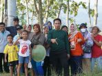 Foto Ketua DPRD Pacitan Arif Setia Budi (tengah, kemeja hijau) berpose akrab bersama warga dan anak-anak di area persawahan Pacitan, dengan latar belakang pohon dan bukit.