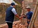 Wakil Bupati Pacitan, Gagarin, mengenakan rompi hitam sedang bersalaman dengan seorang warga pria di tengah reruntuhan bangunan rumah akibat gempa bumi di Lingkungan Gantung.
