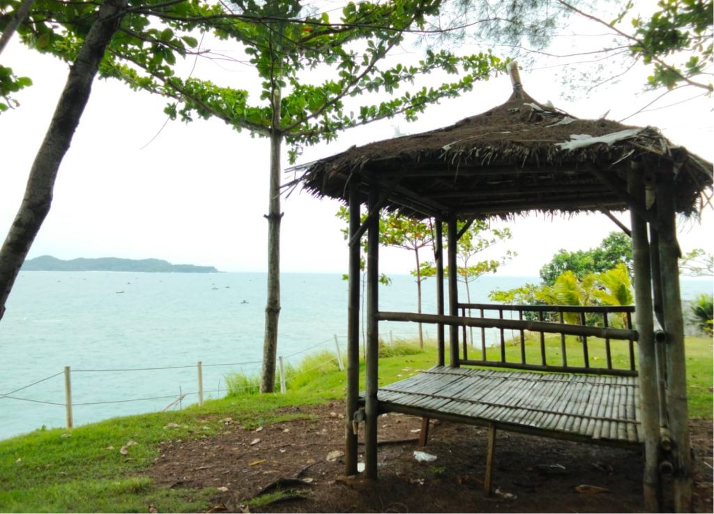 Panorama luas tebing karang megah dan Samudra Hindia di Pantai Watu Bale Pacitan yang tersinari cahaya matahari sore menjelang terbenam.