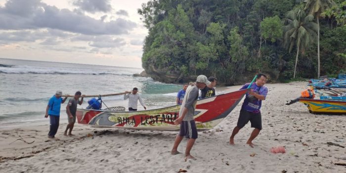 Seorang nelayan Pantai Wawaran berdiri di atas perahu merapikan jaring saat cuaca mendung pada musim penghujan di bulan Februari.