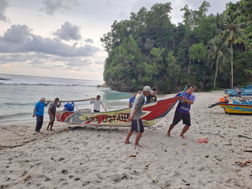 Seorang nelayan Pantai Wawaran berdiri di atas perahu merapikan jaring saat cuaca mendung pada musim penghujan di bulan Februari.