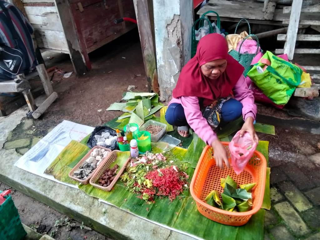 Seorang pedagang perempuan lanjut usia menjual bunga tabur, daun pandan, dan perlengkapan nyekar lainnya di pasar tradisional di Pacitan.