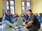 Direktur Pacitanku Digital Media, Sulthan Shalahuddin (kanan, berbaju hitam) menerima berkas penyerahan mahasiswa magang dari Dosen Pembimbing Lapangan (DPL) STKIP PGRI Pacitan, Mufida Yuni Pureka (kiri, berhijab biru), dengan latar belakang mahasiswa berjaket almamater biru di kantor Pacitanku, Senin (9/2/2026).