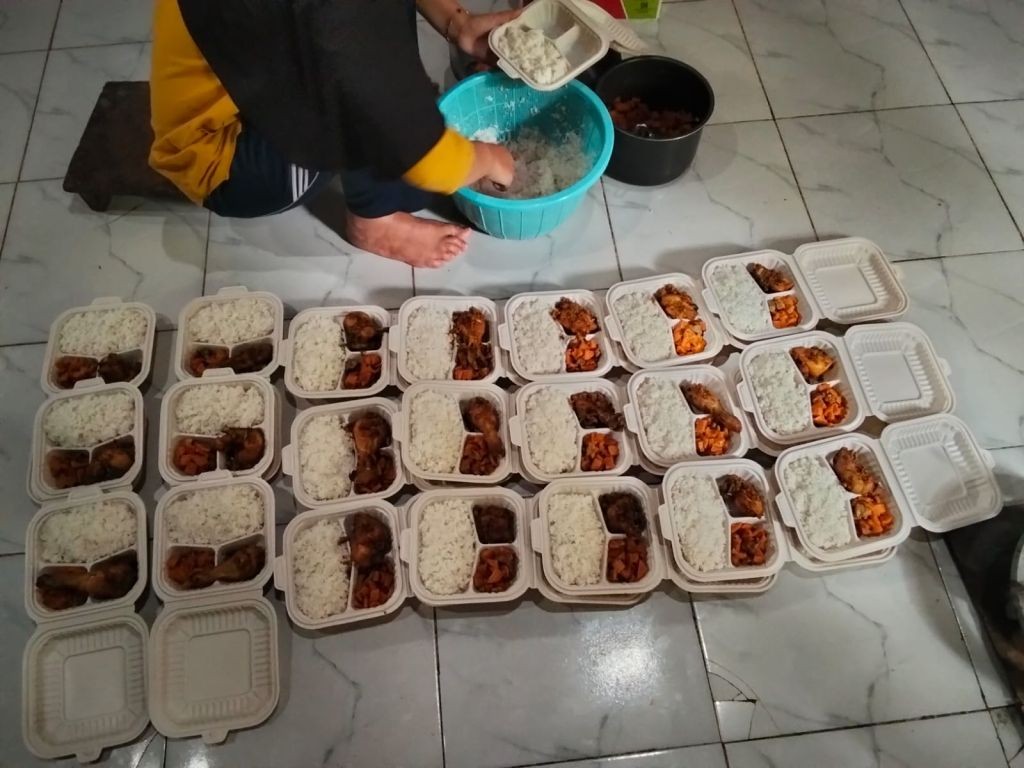 Seorang warga menyiapkan puluhan nasi kotak berisi lauk ayam untuk dibagikan kepada tetangga dalam tradisi megengan di Pacitan jelang Ramadhan.