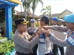 Wakapolres Pacitan berseragam lengkap menyematkan pita operasi berwarna biru secara simbolis kepada perwakilan personel polisi beraret biru dalam apel gelar pasukan.