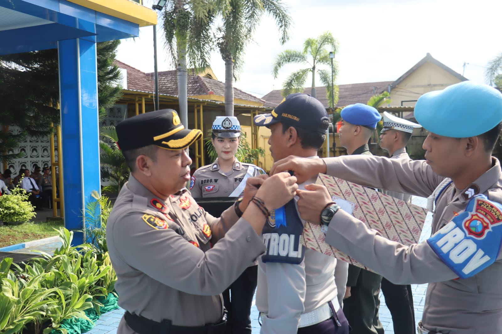 Wakapolres Pacitan berseragam lengkap menyematkan pita operasi berwarna biru secara simbolis kepada perwakilan personel polisi beraret biru dalam apel gelar pasukan.