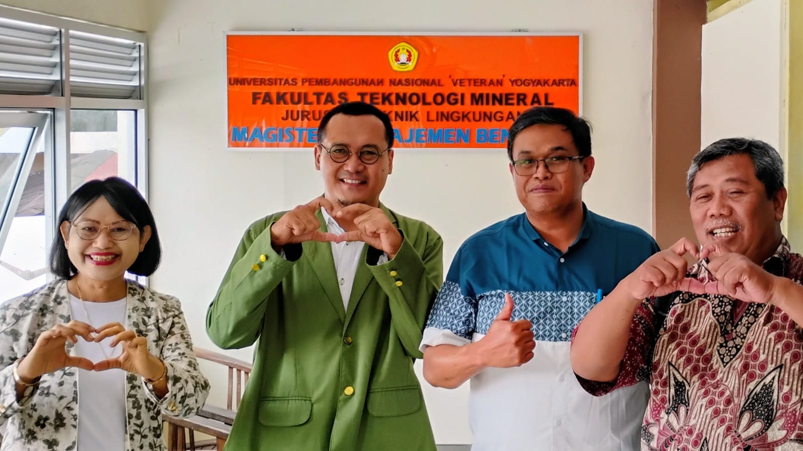 Sebuah foto kelompok berisi empat orang, termasuk Purwoto yang mengenakan jas almamater hijau, bersama tiga dosen pembimbingnya di depan spanduk oranye bertuliskan "UNIVERSITAS PEMBANGUNAN NASIONAL 'VETERAN' YOGYAKARTA FAKULTAS TEKNOLOGI MINERAL JURUSAN TEKNIK LINGKUNGAN MAGISTER MANAJEMEN BENCANA". Mereka berpose dengan senyum, beberapa membentuk simbol hati dengan tangan dan satu orang mengacungkan jempol.