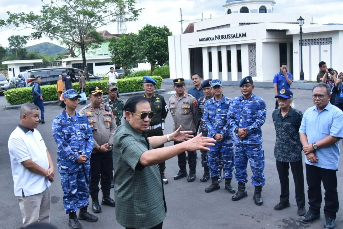 Presiden ke-6 RI Susilo Bambang Yudhoyono (SBY) mengenakan kemeja kotak-kotak hijau dan kacamata hitam sedang berdiskusi dengan Sekretaris Daerah Pacitan dan aparat keamanan berseragam di depan Mushola Nurussalam, kawasan Museum SBY Ani, Pacitan.