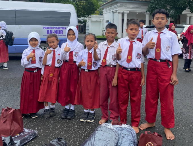 Potret wajah ceria dan senyum lebar anak-anak duafa yang sedang memegang paket alat tulis, bingkisan kue, dan amplop santunan di aula Pendopo Kabupaten Pacitan.