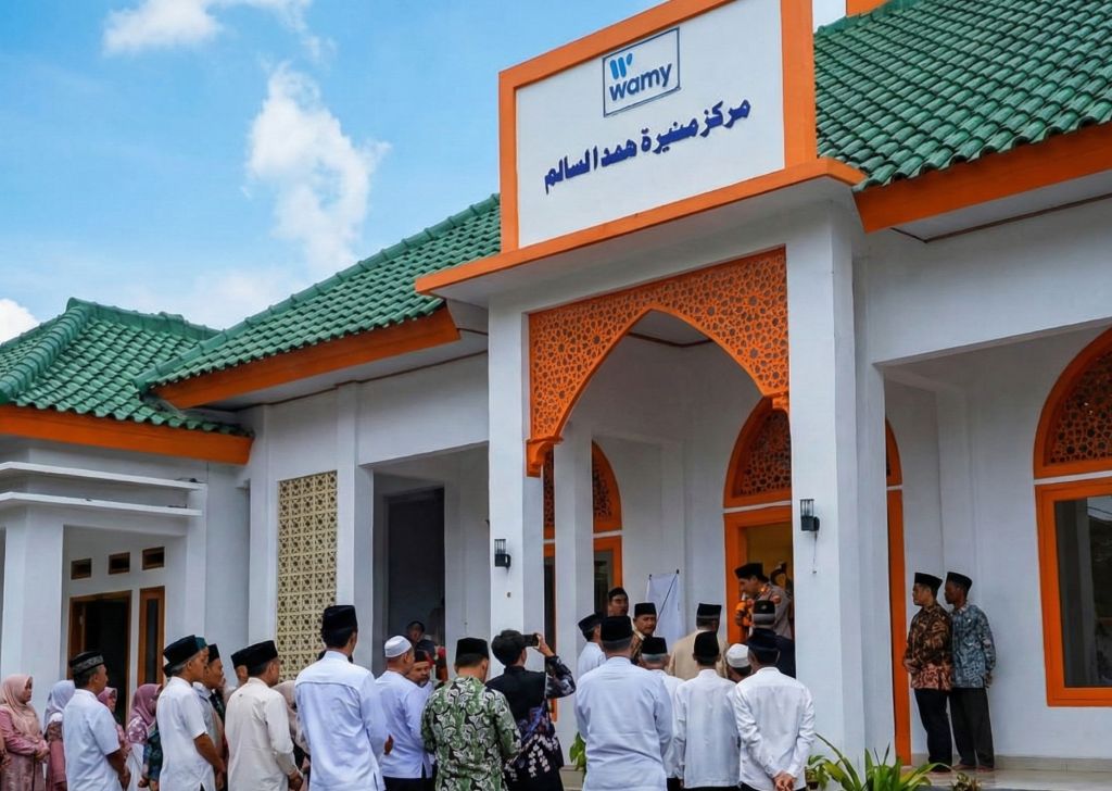 Suasana peresmian Masjid Muniroh Hamad Al-Salim bantuan WAMY di Kelurahan Ploso, Pacitan, dengan warga dan tokoh masyarakat berkumpul di depan pintu masuk bangunan masjid berwarna putih dengan aksen oranye dan atap hijau.