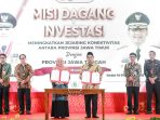Suasana panggung utama acara Misi Dagang dan Investasi antara Provinsi Jawa Timur dan Jawa Tengah. Terlihat Gubernur Khofifah Indar Parawansa (kiri) dan Wakil Gubernur Taj Yasin Maimoen (kanan) memegang dokumen perjanjian di belakang meja, dengan latar belakang layar besar bergambar foto mereka dan tulisan "MISI DAGANG & INVESTASI".