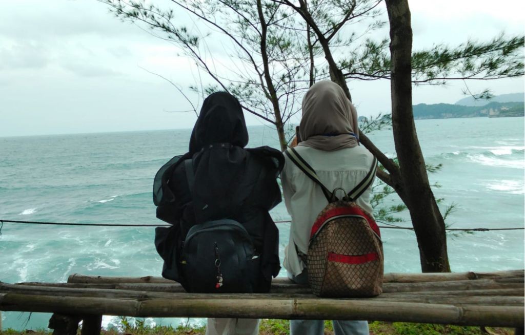 Sebuah bangku kayu menghadap Samudra Hindia dengan latar langit senja di Watu Bale.