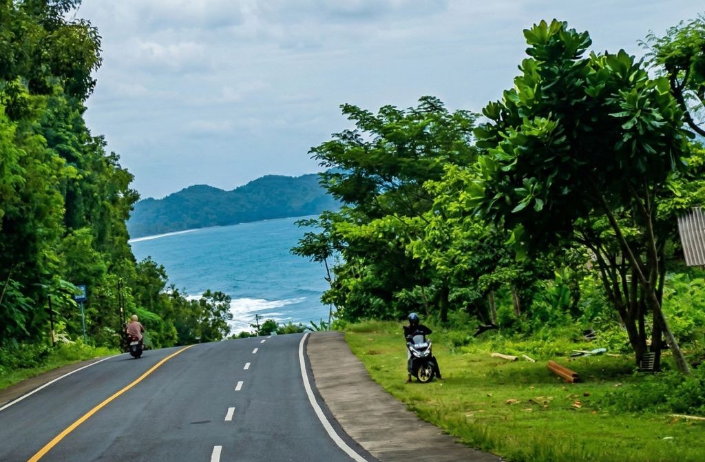 Kondisi jalan aspal Jalur Lintas Selatan (JLS) yang membentang persis di pinggir hamparan pasir dan ombak Pantai Soge Pacitan.