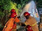 Personel Damkar Pacitan melakukan pendinginan pada truk tangki BBM yang terguling di Jalur Pacitan-Solo.