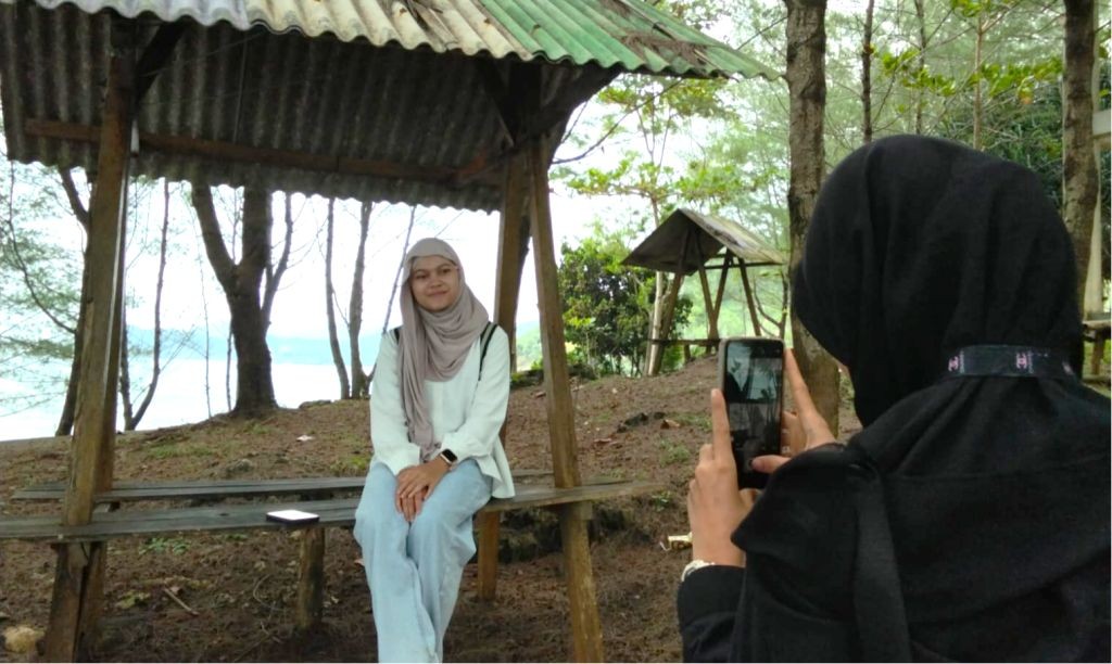 Gazebo kayu dengan latar pepohonan rindang dan laut biru di kawasan wisata Watu Bale.