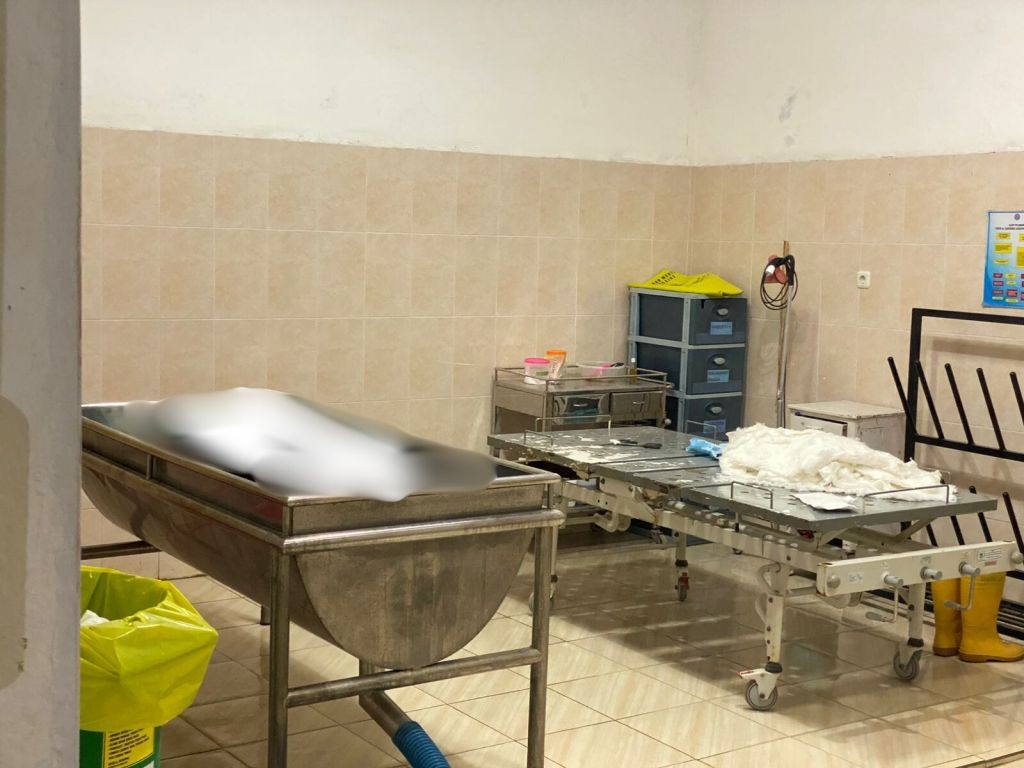 Jasad Dinar Adjie Mukti Wibowo yang telah ditutupi di atas brankar ruang jenazah RSUD dr. Darsono Pacitan pascaproses identifikasi.