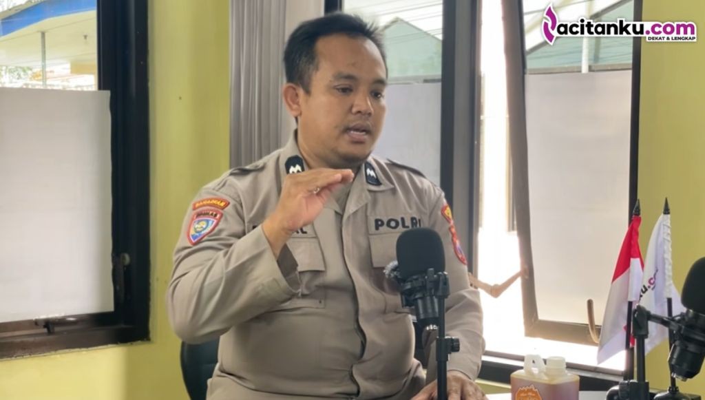 Rizhal Adarriyanto, anggota Polres Pacitan, sedang memberi pakan ayam di kandang panggung inovatif miliknya.