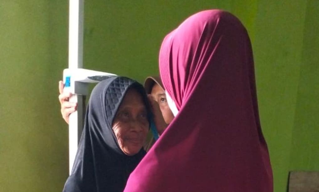 Seorang warga lanjut usia (lansia) di Desa Sidomulyo sedang melakukan pengukuran tinggi badan dan pemeriksaan kesehatan rutin di Posyandu.