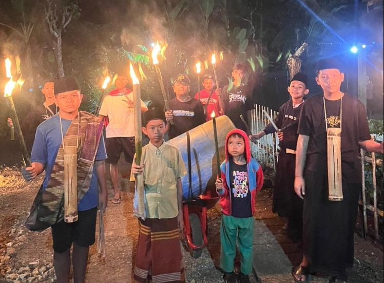 Puluhan anak dan remaja masjid membawa obor berjalan kaki menyusuri gang sempit saat takbir keliling.