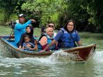Wisatawan menyusuri keindahan alam Sungai Maron Pacitan menggunakan perahu saat libur Lebaran 2026.