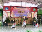 Kelompok siswi SD menampilkan tarian tradisional dengan kostum lengkap berwarna merah keemasan dalam lomba Seni Tari FLS2N Kecamatan Tulakan 2026 di SDN Bungur.