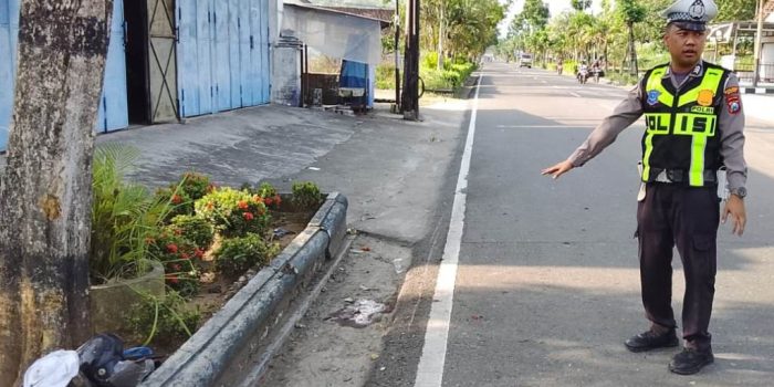 Petugas Satlantas Polres Pacitan menunjukkan lokasi pasti kecelakaan tunggal maut yang melibatkan sepeda motor pelajar di depan SPBU Nanggungan, Pacitan. Polisi menunjuk ke area taman yang rusak.