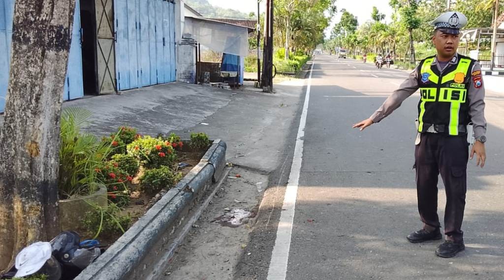 Petugas Satlantas Polres Pacitan menunjukkan lokasi pasti kecelakaan tunggal maut yang melibatkan sepeda motor pelajar di depan SPBU Nanggungan, Pacitan. Polisi menunjuk ke area taman yang rusak.