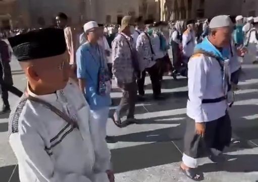 Rombongan jemaah haji Indonesia asal Kabupaten Pacitan (Kloter 25) mengenakan seragam batik batik haji, sedang beraktivitas ibadah di pelataran Masjid Nabawi, Madinah, dengan latar belakang payung raksasa dan menara masjid.