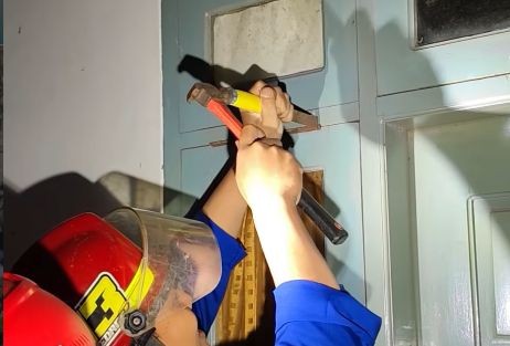 Petugas Damkar Pacitan sedang membuka pintu kamar kos yang terkunci.