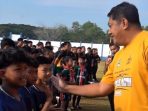 Gagarin Semangati Peserta Piala Kapolres Pacitan 2026 Wakil Bupati Pacitan Gagarin tersenyum sambil melakukan 'tos' high-five dengan anak peserta turnamen sepak bola usia dini di lapangan.
