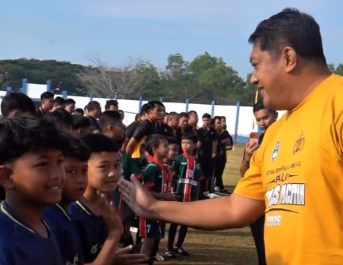 Gagarin Semangati Peserta Piala Kapolres Pacitan 2026 Wakil Bupati Pacitan Gagarin tersenyum sambil melakukan 'tos' high-five dengan anak peserta turnamen sepak bola usia dini di lapangan.