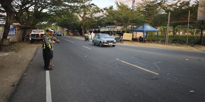 Anggota Satlantas Polres Pacitan melakukan olah TKP, mengukur jarak benturan antara sepeda motor Yamaha Vega merah marun dan truk kuning di simpang tiga Sirnoboyo.