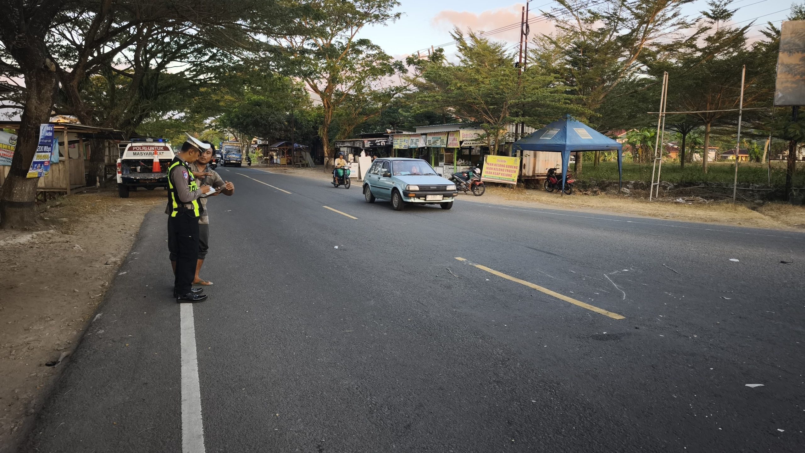 Anggota Satlantas Polres Pacitan melakukan olah TKP, mengukur jarak benturan antara sepeda motor Yamaha Vega merah marun dan truk kuning di simpang tiga Sirnoboyo.