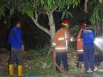 Petugas Damkar Pacitan memadamkan api pada kebakaran lahan kosong di Kelurahan Sidoharjo akibat pembakaran sampah.