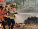 Petugas Damkar Pacitan memadamkan kebakaran tumpukan limbah kayu lapis di CV Sengon Indah Kebonagung.