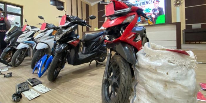 Foto barang bukti kasus pencurian umbi porang di Polres Pacitan. Di sebelah kanan, terlihat satu karung putih berisi umbi porang yang penuh dan sepeda motor Honda Beat warna hitam yang digunakan pelaku. Di area tengah, terdapat tas selempang, pisau, dompet, KTP, dan tumpukan nota penjualan porang yang tersusun rapi.
