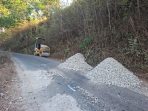 Alat berat dan tumpukan material batu koral serta aspal bersiaga di tepi jalan rusak kawasan Sengkan Selang, Tegalombo, Pacitan.