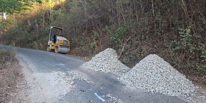 Alat berat dan tumpukan material batu koral serta aspal bersiaga di tepi jalan rusak kawasan Sengkan Selang, Tegalombo, Pacitan.